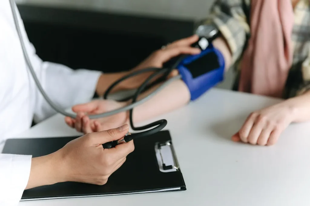 A health worker measuring blood pressure using a manual blood pressure cuff on the right arm of a patient