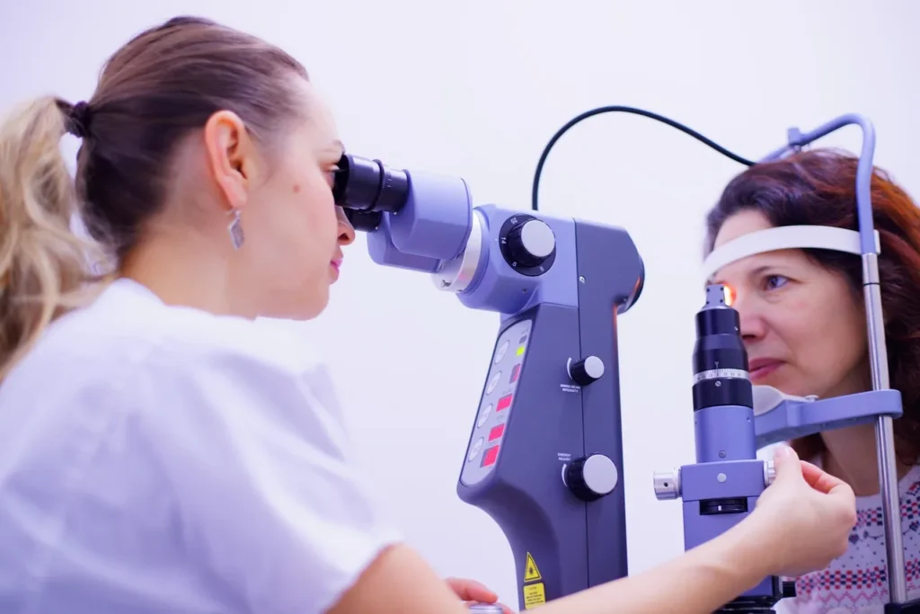 An eye doctor using a slit lamp to check for signs of hypertensive retinopathy in a person's eyes.