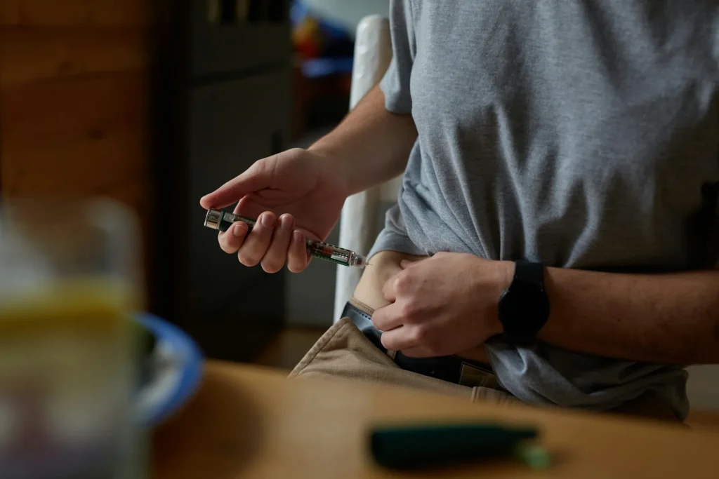 Man with diabetes injecting insulin into the right side of the abdomen.