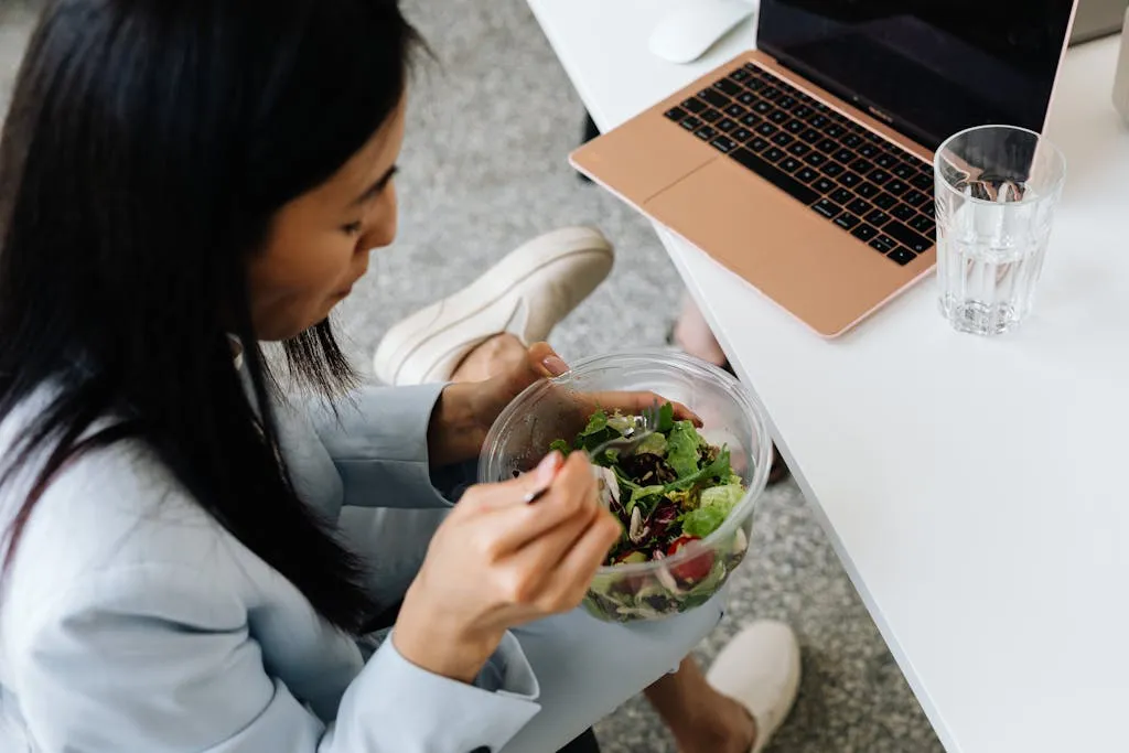 Close up shot of a woman eating vegetables from a transparent bowl.