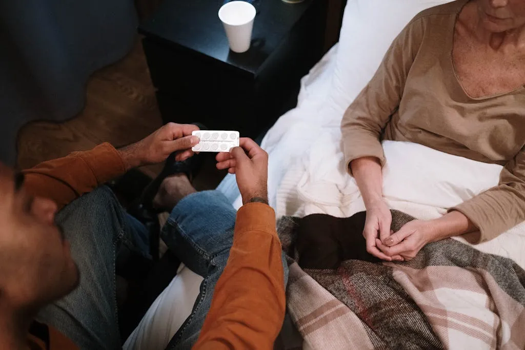 Man giving medicine to an elderly woman in bed.