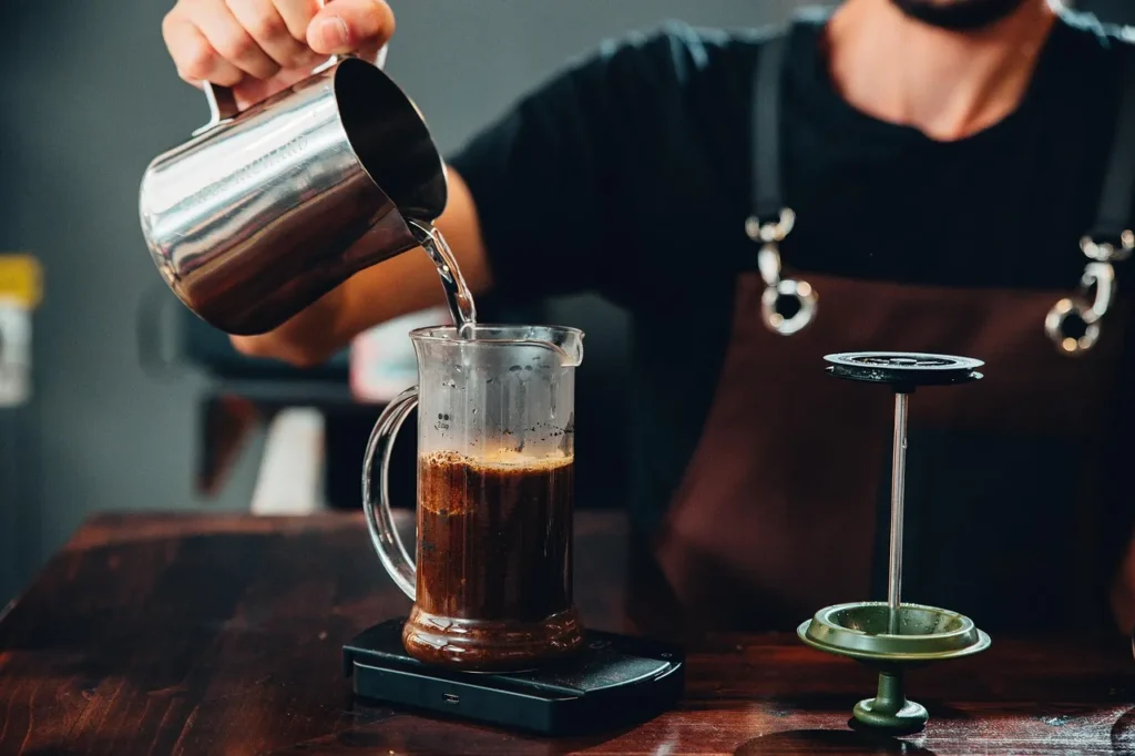 Person making specialty coffee in a transparent mug.