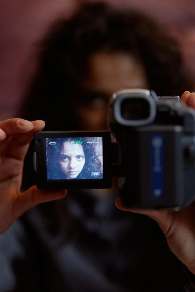 Woman holding a video camera with her face visible on the screen.