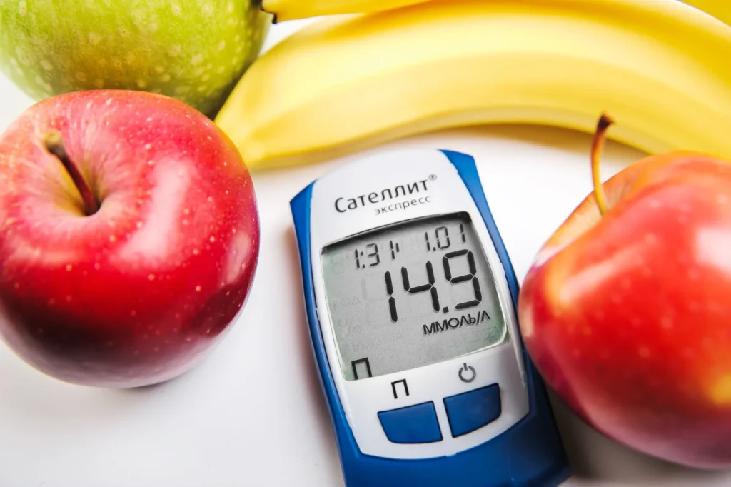 Two red apples, a green apple and a yellow banana around a glucose meter