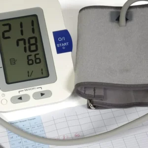 Digital blood pressure cuff and medical chart on a white surface