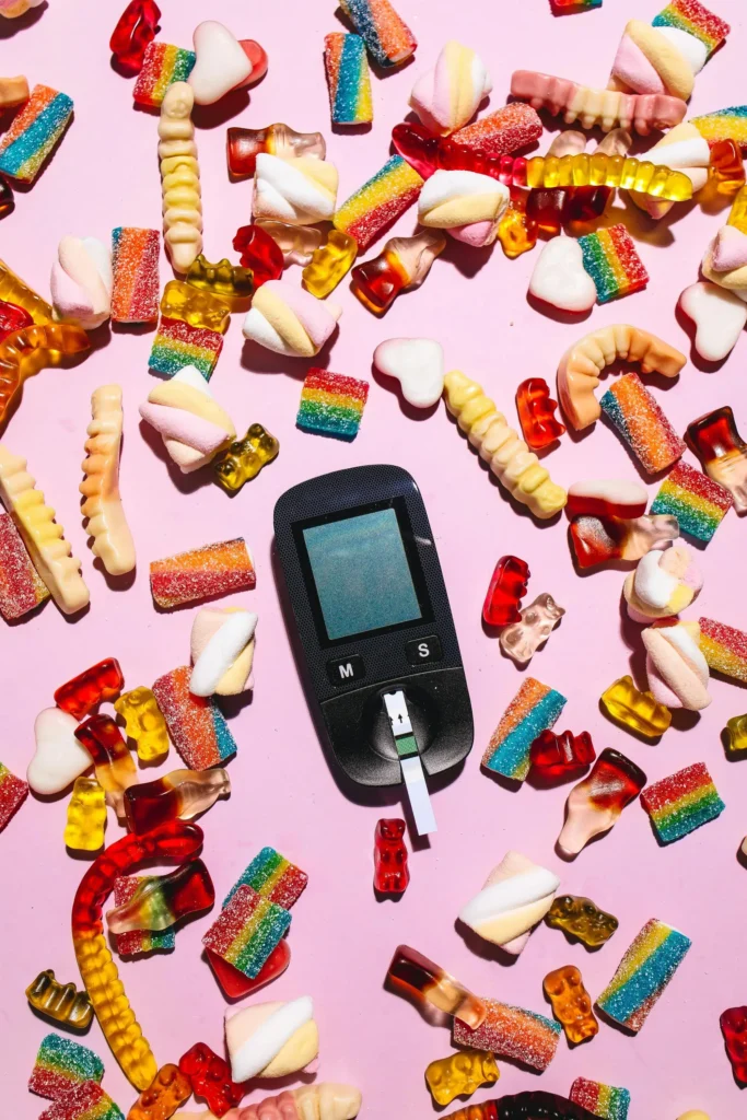 A glucose meter surrounded by many types and shapes of processed sweets.